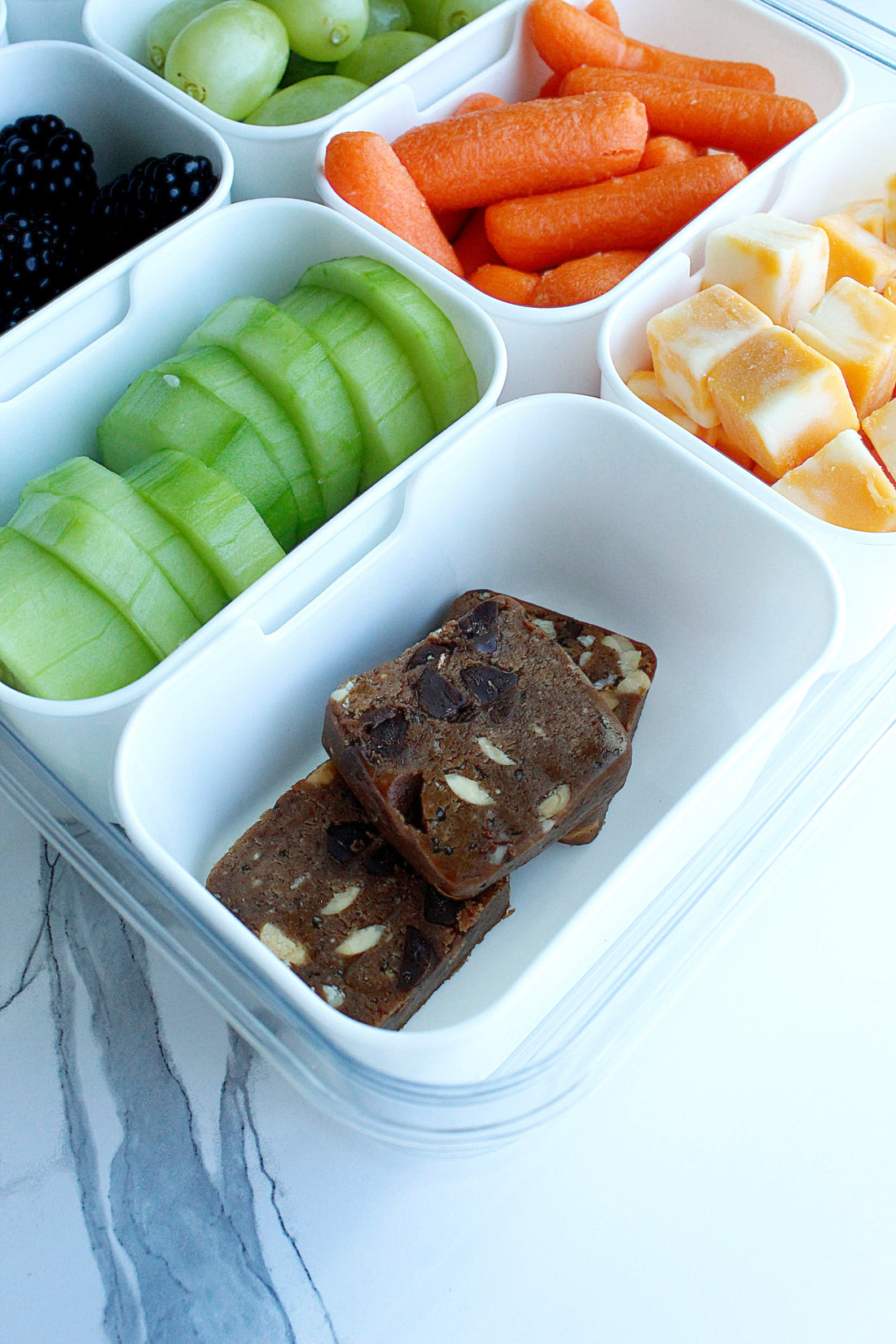 Photo of white plastic lunch box with various veggies, cheese, and E3 Protein Cubes