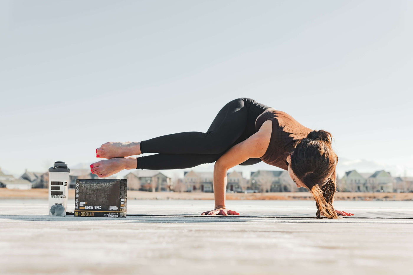 Beautiful girl doing Yoga pose with E3 Energy Cubes bars and shaker bottle.  Peanut Butter + Chocolate.  Gluten-free, Dairy-free, Soy-free, Non-gmo, All natural protein bars.